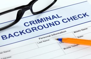 Criminal background check application form alongside pen and glasses for job applicants to fill out